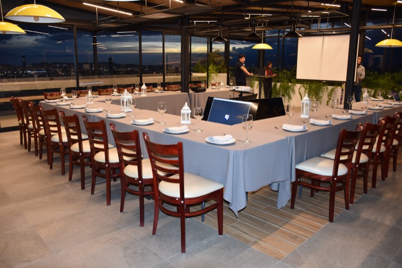 Montaje en U para evento corporativo con pantalla de proyección en la terraza de Bistro 702, con vista panorámica de Puebla al anochecer