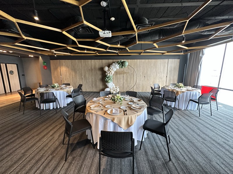 Salón privado de Bistro 702 con mesas redondas, mantelería beige y arco de globos para celebración