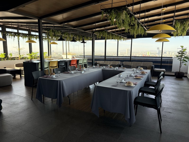 Desayuno de grupo montado en U en la terraza jardín de Bistro 702 con vista a la ciudad de Puebla
