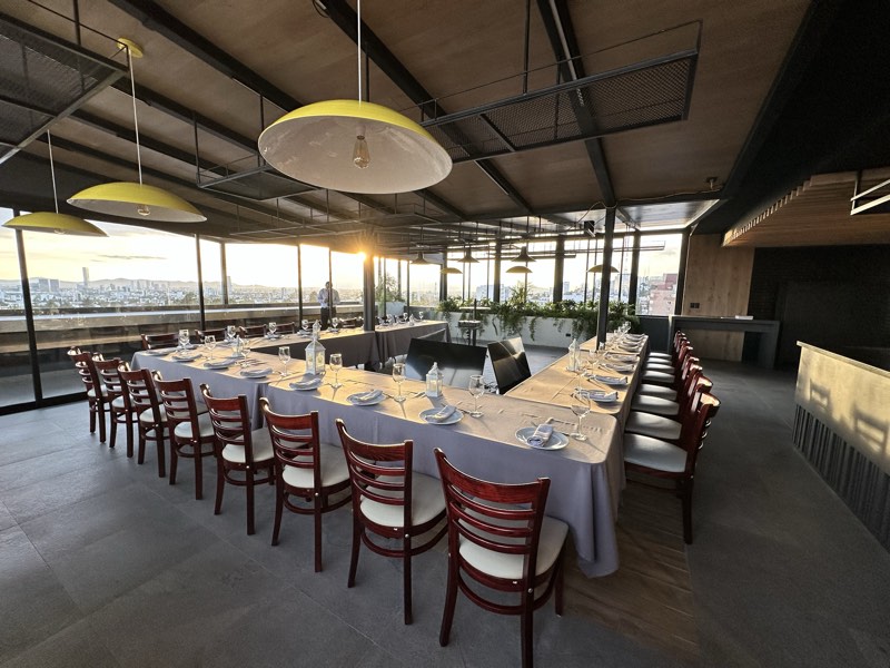 Mesa imperial montada con cristalería al atardecer en la terraza panorámica de Bistro 702
