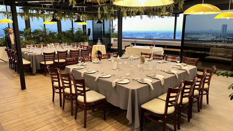 Banquete con manteles grises, velas y follaje colgante en la terraza jardín de Bistro 702